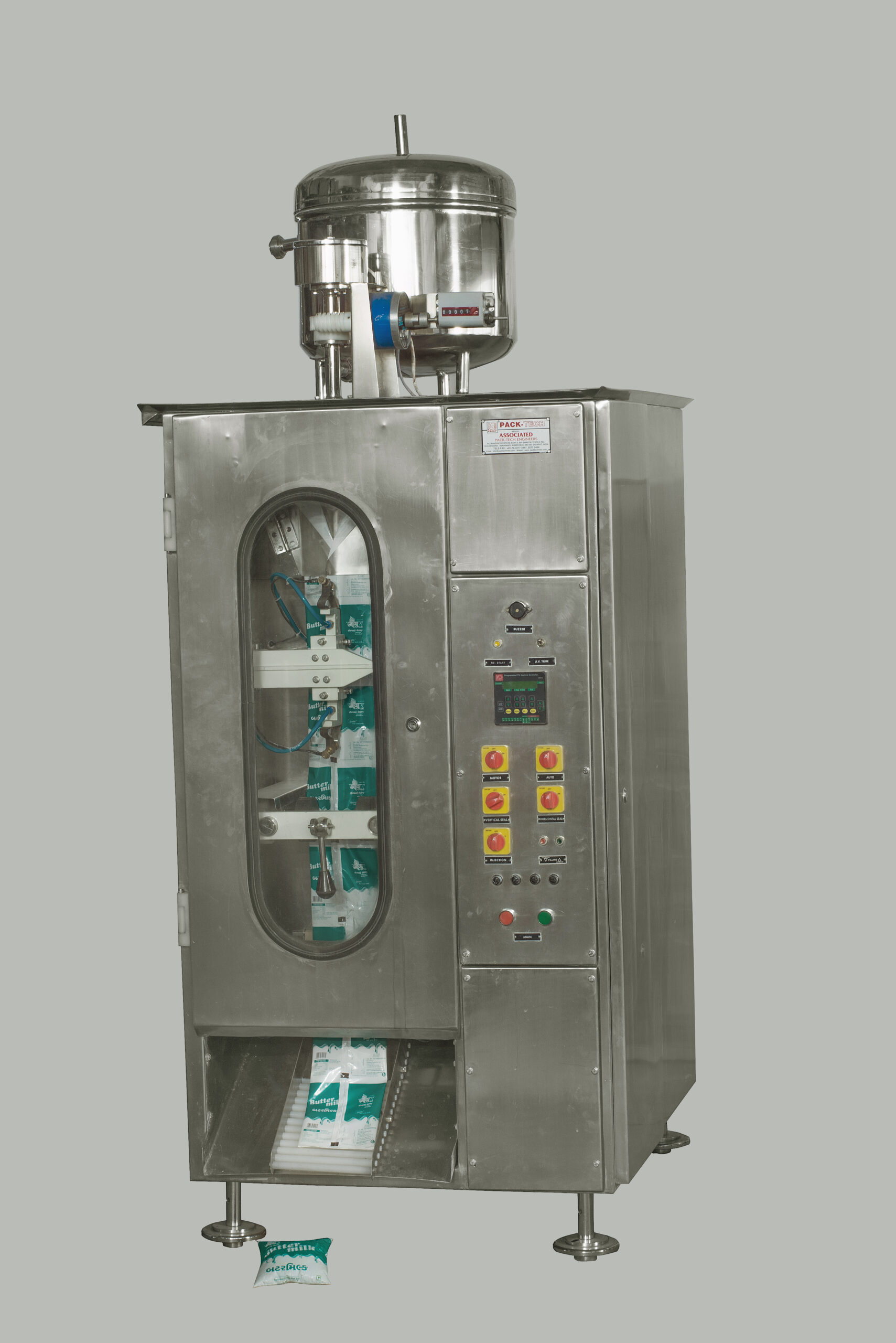 A sleek, stainless steel milk pouch packing machine with a clear viewing panel showcasing the pouch-filling process.